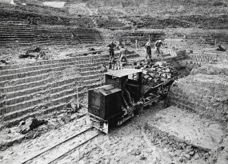 "Ziegelei-Arbeiter Lehm stechend und Feldbahn beladend, Zürcher Ziegeleien" Lehmgrube Tiergarten, Ziegelei-Arbeiter stechen Lehm und beladen die Feldbahn, Zürcher Ziegeleien, Bühlstrasse, Wiedikon, Zürich, 1961 (Baugeschichtliches Archiv, BAZ 163889, Foto